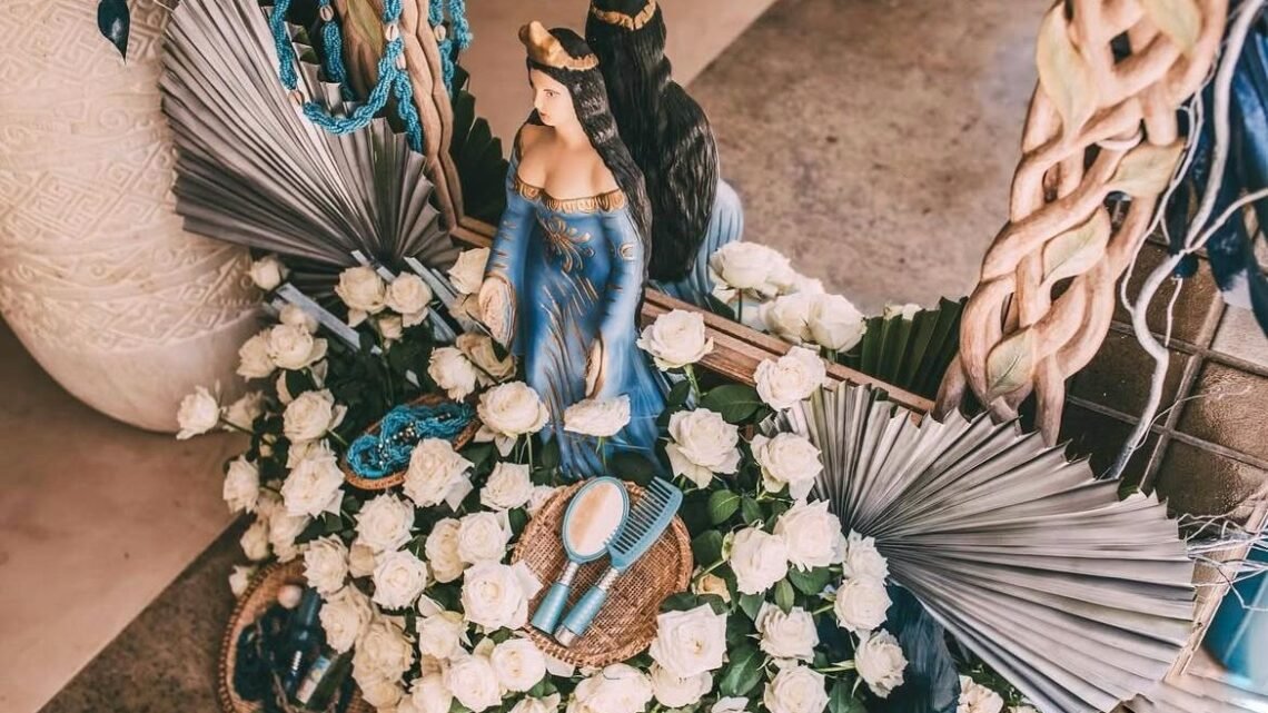 Escultura de Iemanjá decorada com flores brancas e azuis para celebração no Blue Praia Bar.