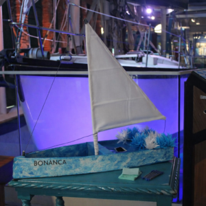 Miniatura do barco Bonança em tons de azul e branco, decorado com flores, para a ação de Iemanjá no Museu do Mar Aleixo Belov.