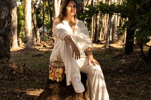 Tereza Carvalho sentada em um tronco de árvore na natureza, vestindo branco e transmitindo a serenidade do conceito ROMO.