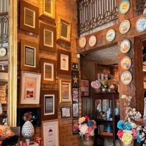 Decoração interna do Restaurante Casa de Tereza no Rio Vermelho com imagens de Iemanjá, flores e pratos da Boa Lembrança na parede.