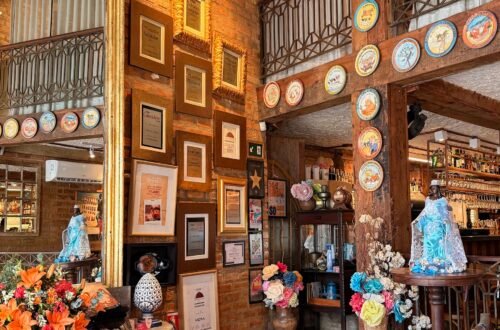 Decoração interna do Restaurante Casa de Tereza no Rio Vermelho com imagens de Iemanjá, flores e pratos da Boa Lembrança na parede.