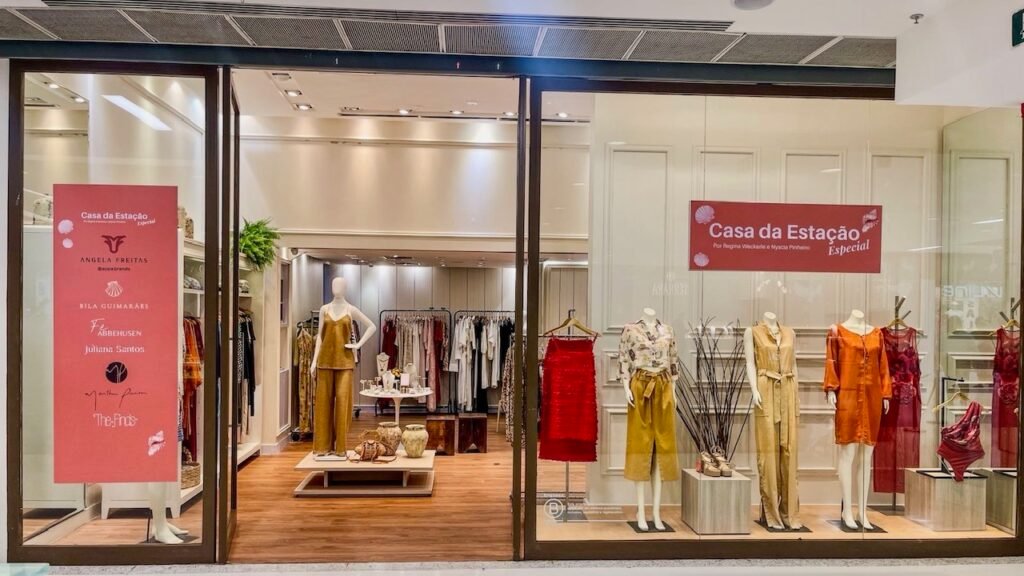 Fachada da loja Casa da Estação no Shopping Barra com manequins na vitrine e banner vermelho listando as marcas participantes.