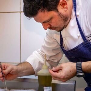 Chef Filipe Rizzato prepara prato na cozinha durante jantar especial de 20 anos do Restaurante Amado em Salvador.