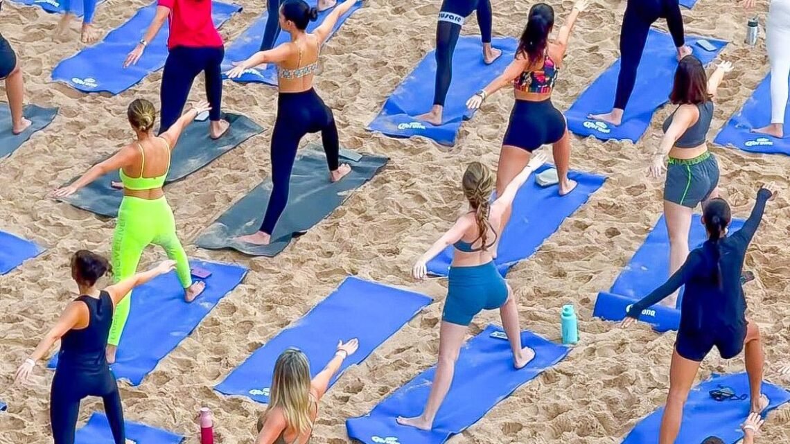 Aula de yoga ao amanhecer no Blue Praia com participantes na areia da Praia do Buracão em Salvador