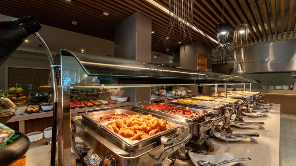 Buffet de pratos quentes do restaurante Sabores de Itapuã com opções de guarnições e carnes para o almoço.