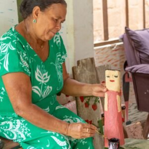 Vanusa pinta escultura em madeira à mão em Alagoas, técnica tradicional do artesanato local.