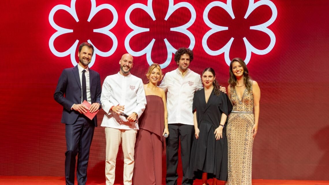 Cerimônia do Guia Michelin Brasil 2026 com chefs premiados e representantes no palco diante do símbolo das três estrelas