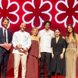 Cerimônia do Guia Michelin Brasil 2026 com chefs premiados e representantes no palco diante do símbolo das três estrelas