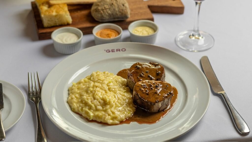 Prato de filé ao poivre vert acompanhado de risoto de alho-poró, servido em louça branca com a logomarca Gero.