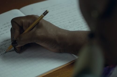 Pessoa escreve em um caderno em cena da série Elas no Singular, que retrata a trajetória de oito escritoras brasileiras e seus processos de criação literária.