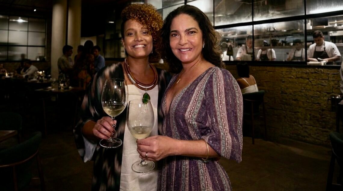 ConfraDelas no Silva Cozinha com a sommelière Carol Souzah e Luciana Mastique, sócia do restaurante, segurando taças de vinho.