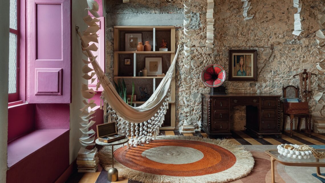 Ambiente da Casacor Bahia 2026 na Casa Nossa Senhora das Mercês, em Salvador, com rede, livros suspensos e elementos que valorizam arte, arquitetura e patrimônio histórico.