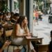 Mulher observa a rua em um café enquanto outras pessoas usam o celular