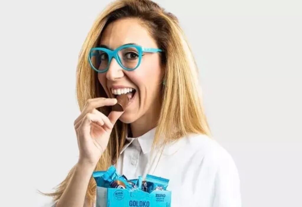 Chantal Goldfinger, cofundadora que participará da estreia da GoldKo na Bahia, segura um chocolate próximo à boca.