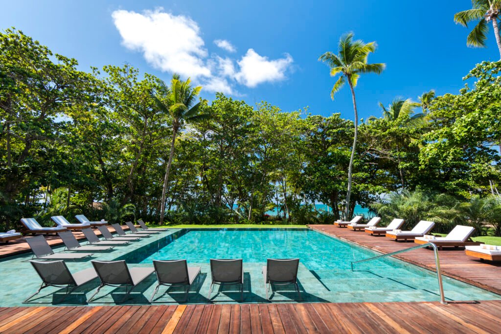 Piscina do Anantara Spa, com espreguiçadeiras na água, deque de madeira e coqueiros ao redor.