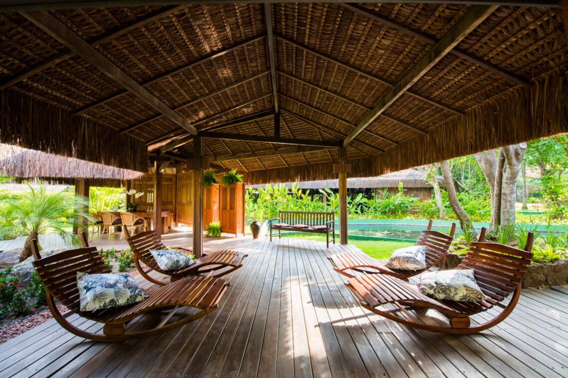 Área de descanso do Anantara Spa, com espreguiçadeiras de madeira sob cobertura de palha e jardins ao redor.