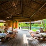 Área de descanso do Anantara Spa, com espreguiçadeiras de madeira sob cobertura de palha e jardins ao redor.