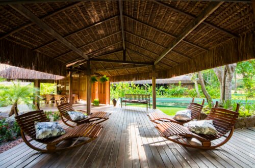 Área de descanso do Anantara Spa, com espreguiçadeiras de madeira sob cobertura de palha e jardins ao redor.