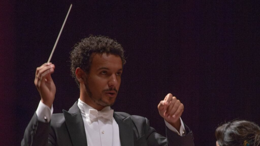Maestro Luiz de Godoy durante uma apresentação, com a batuta erguida.