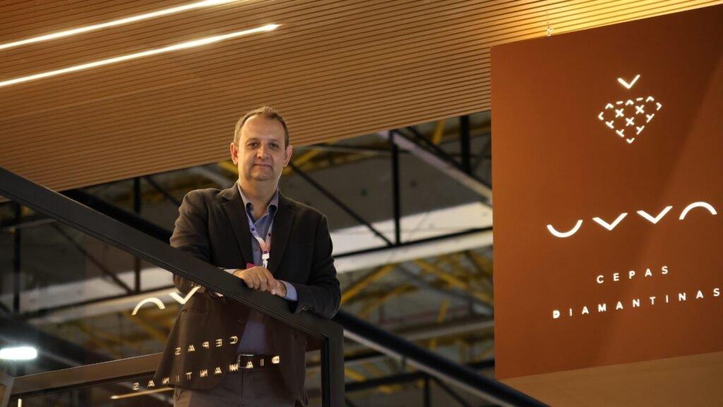 Marcelo Petrolli, enólogo da UVVA, ao lado de um painel com a marca da vinícola.